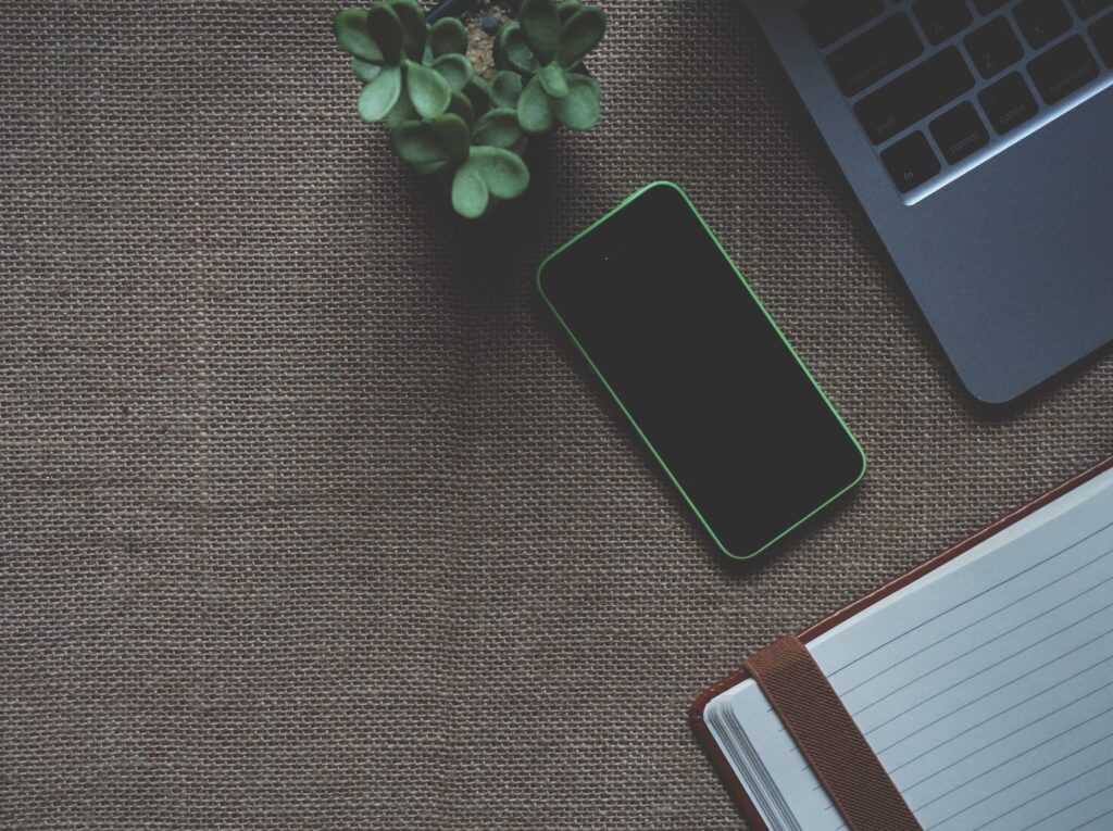 Smartphone, Laptop und Notizbuch auf einem Schreibtisch