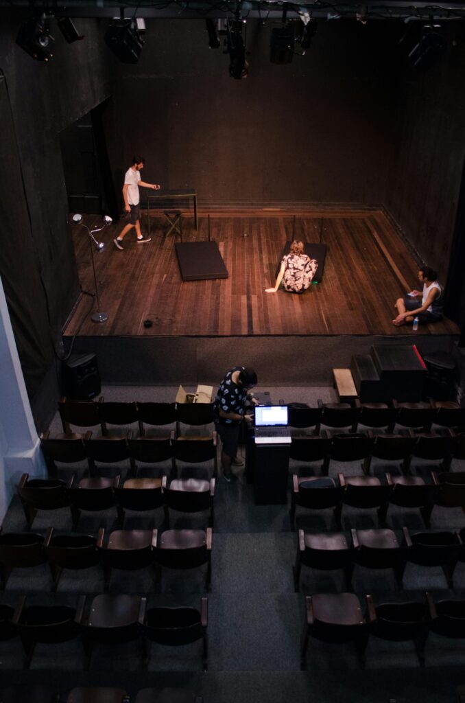 Blick von oben auf eine Theaterbuehne mit Technikerarbeitsplatz im Zuschauerraum